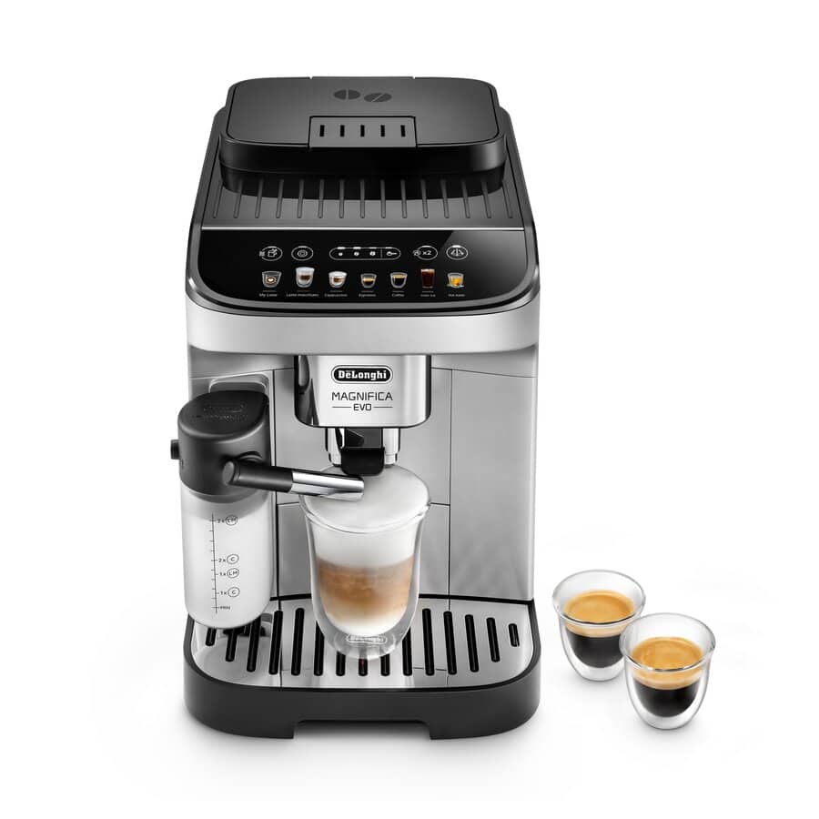 De'Longhi Magnifica Evo ECAM29084SB super-automatic espresso machine in silver — 13-setting stainless conical burr grinder up top, LatteCrema Hot automatic milk-frothing carafe attached on the right, latte macchiato mid-pour into a clear glass on the drip tray.